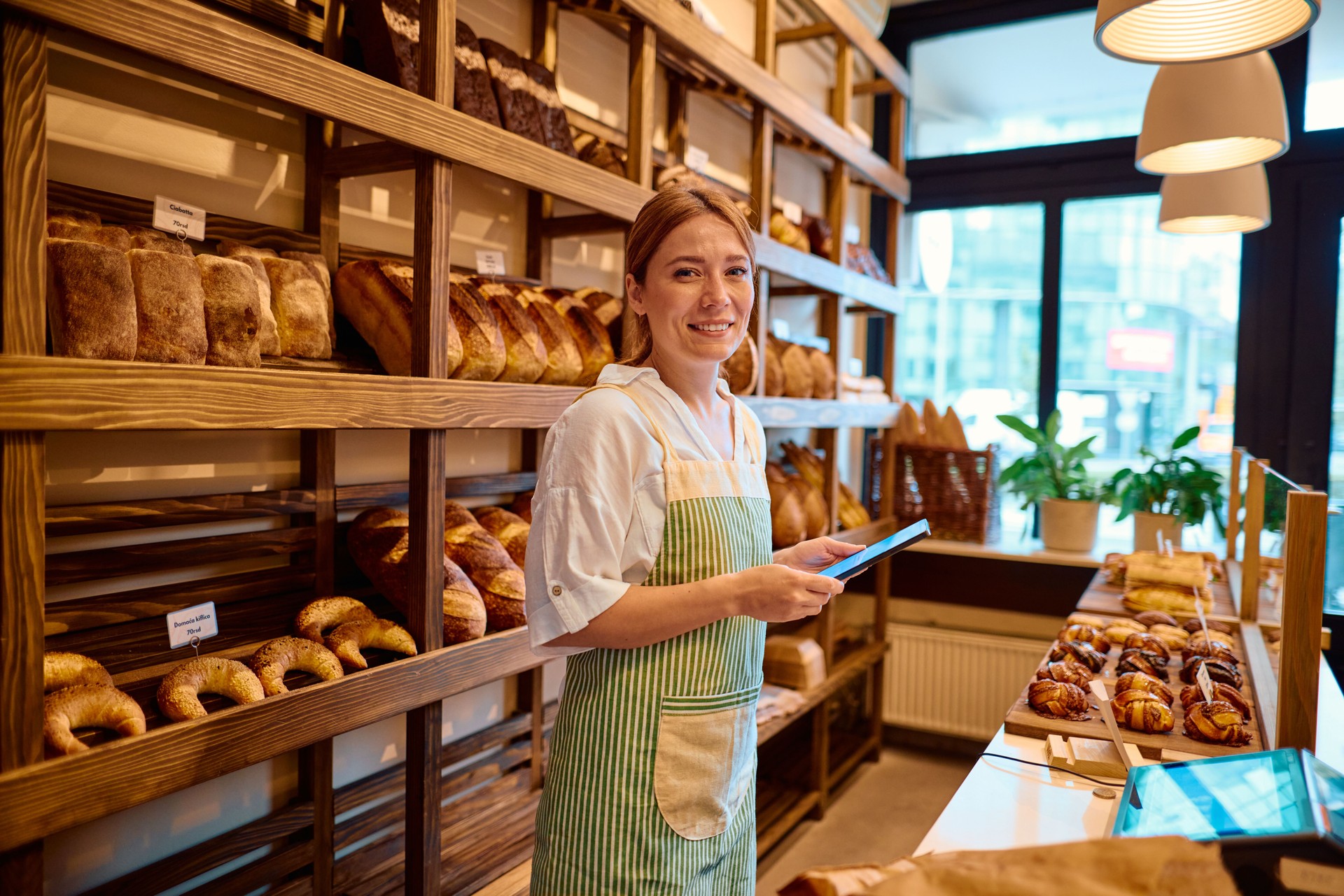 Smiling saleswoman using digital tablet while working in bakery